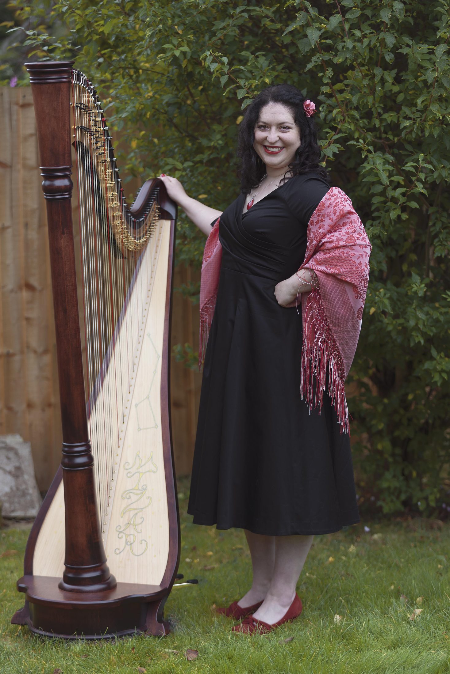 Maria smiling beside her harp in a garden